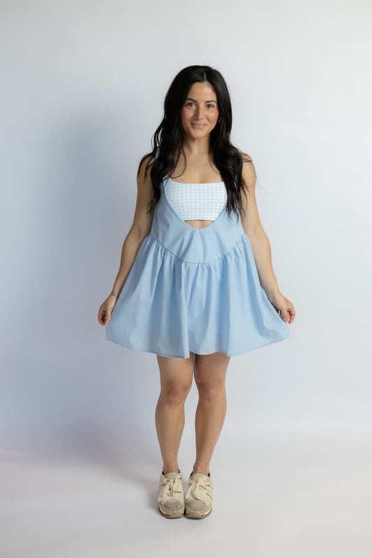 Woman wearing a light blue dress with a white top on a plain background