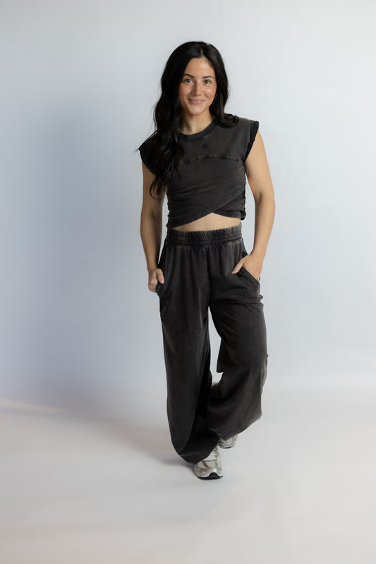 Person wearing a black sleeveless top and wide-leg pants on a white background