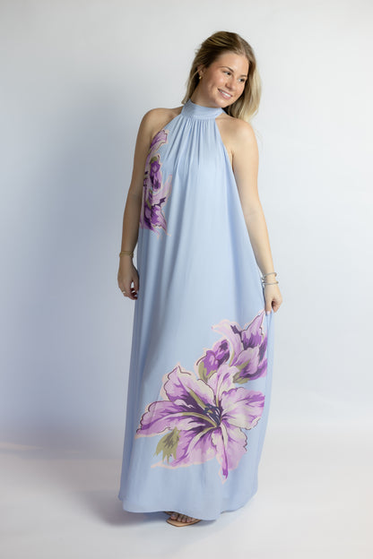 Woman wearing a light blue dress with purple floral patterns on a white background