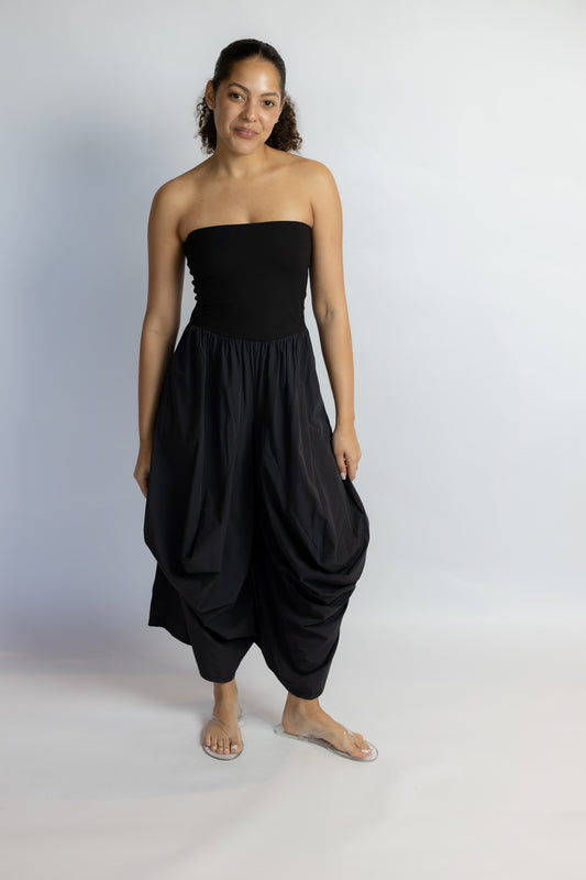 Woman wearing a black strapless harem jumpsuit on a white background