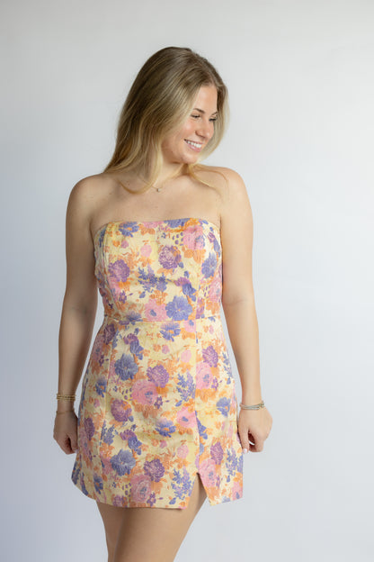 Woman wearing a floral strapless dress on a plain background