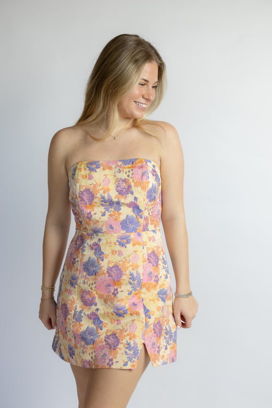 Woman wearing a floral strapless dress on a plain background