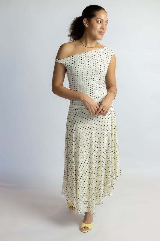 Woman wearing a white dress with black polka dots against a plain background
