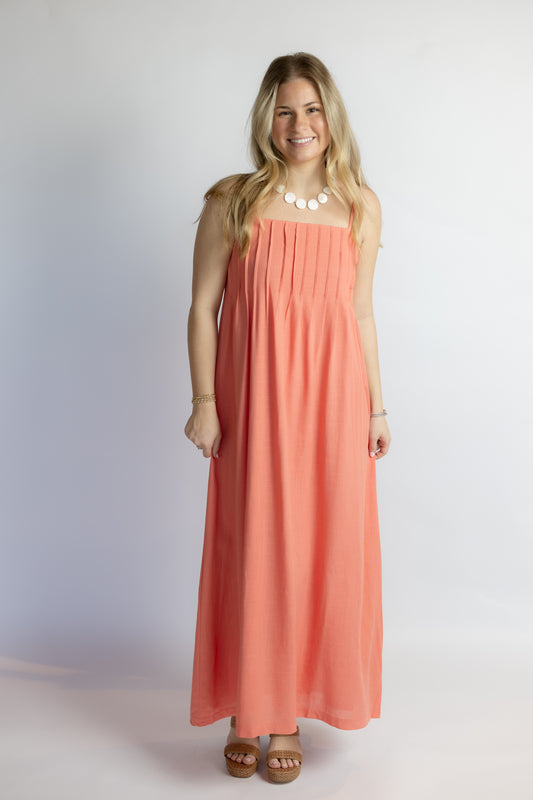 Woman wearing a coral dress against a plain background