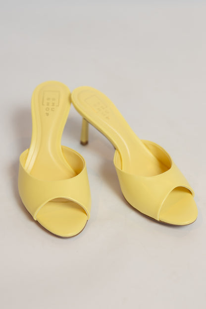 Pair of yellow high-heeled shoes on a light gray background