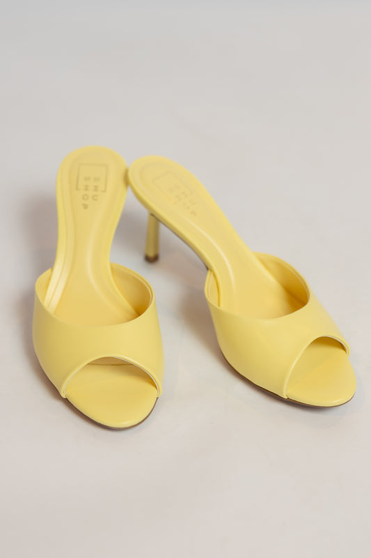 Pair of yellow high-heeled shoes on a light gray background