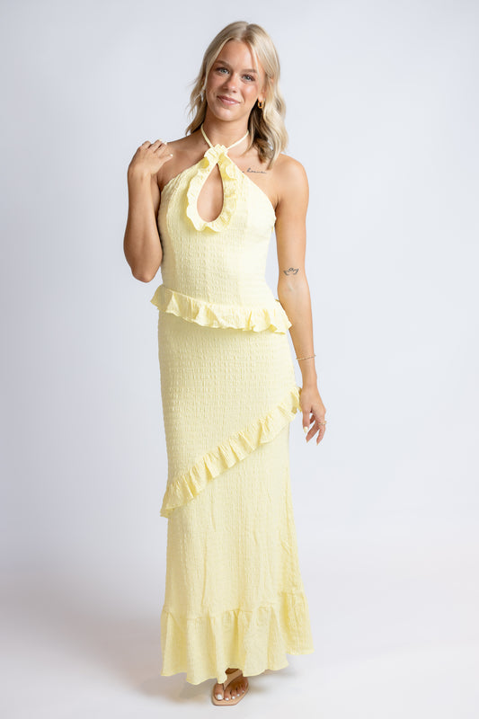 Woman wearing a yellow dress with ruffled details on a white background