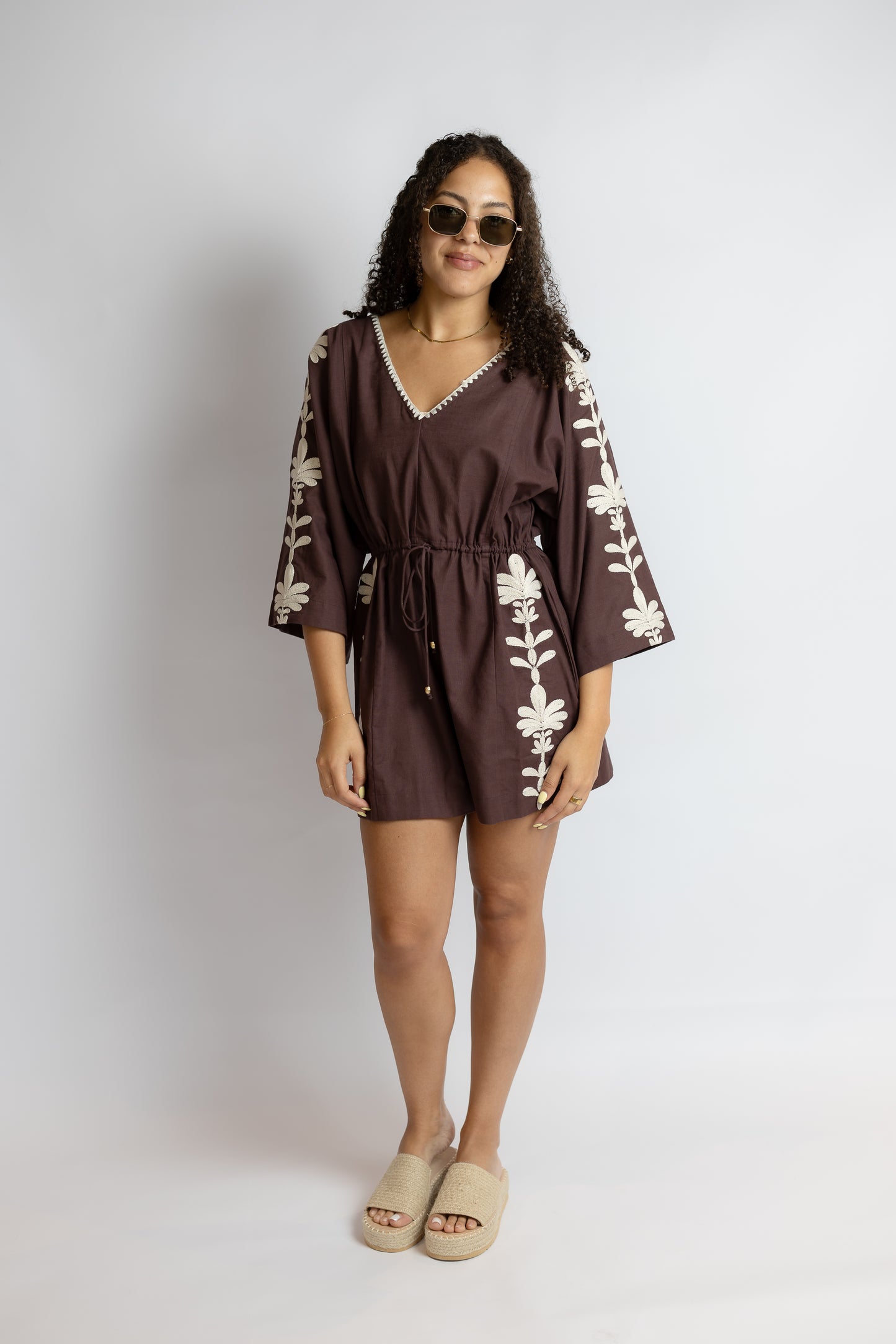Woman wearing a brown dress with floral patterns on a white background