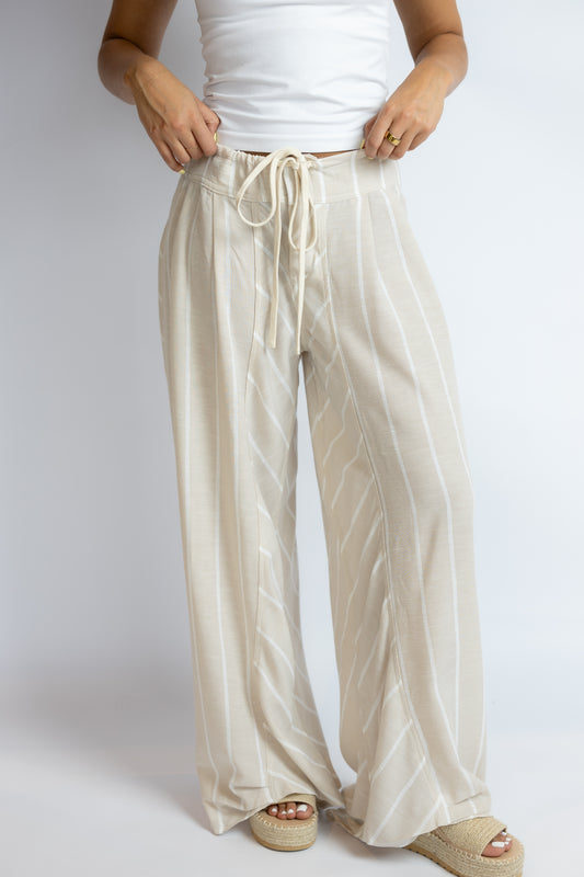 Beige wide-leg pants worn by a person on a white background