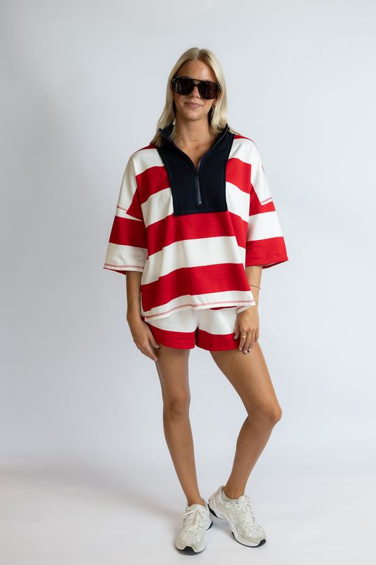 Woman wearing a red and white striped outfit with sunglasses on a plain background