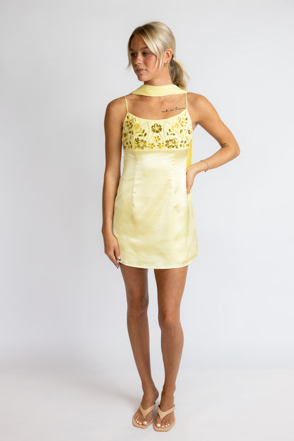 Woman wearing a yellow dress with floral patterns on a white background