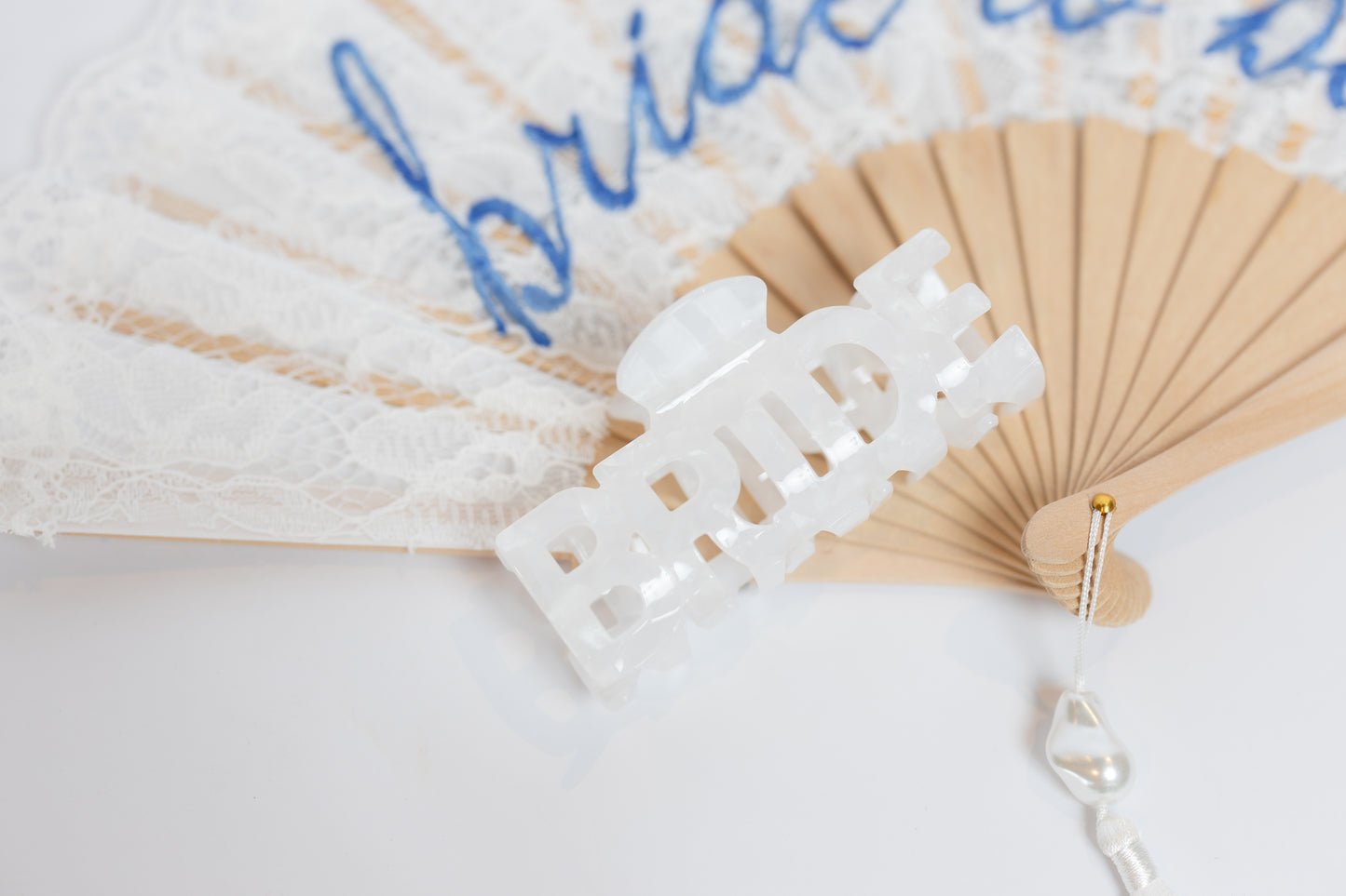 White lace hair clip on a beige fan with 'bride' text on a light background