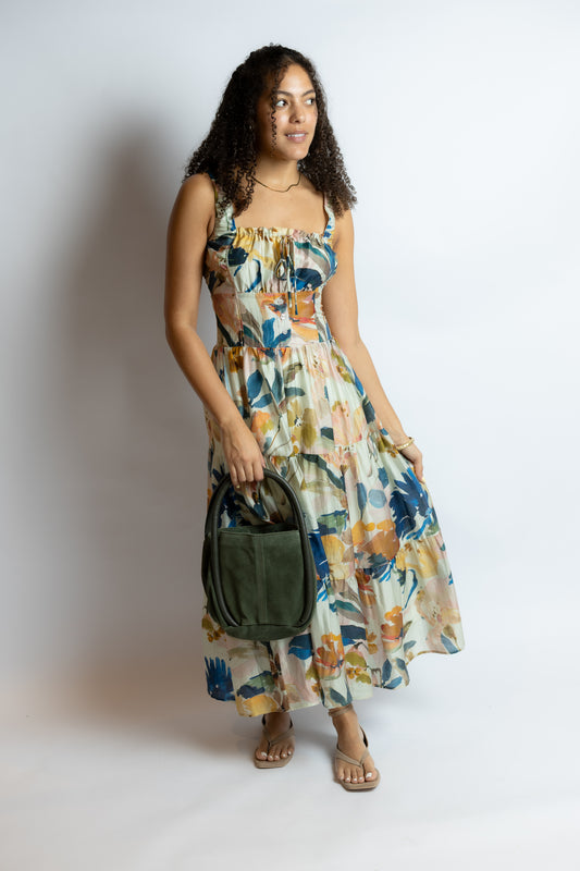 Woman wearing a floral dress holding a green bag against a white background