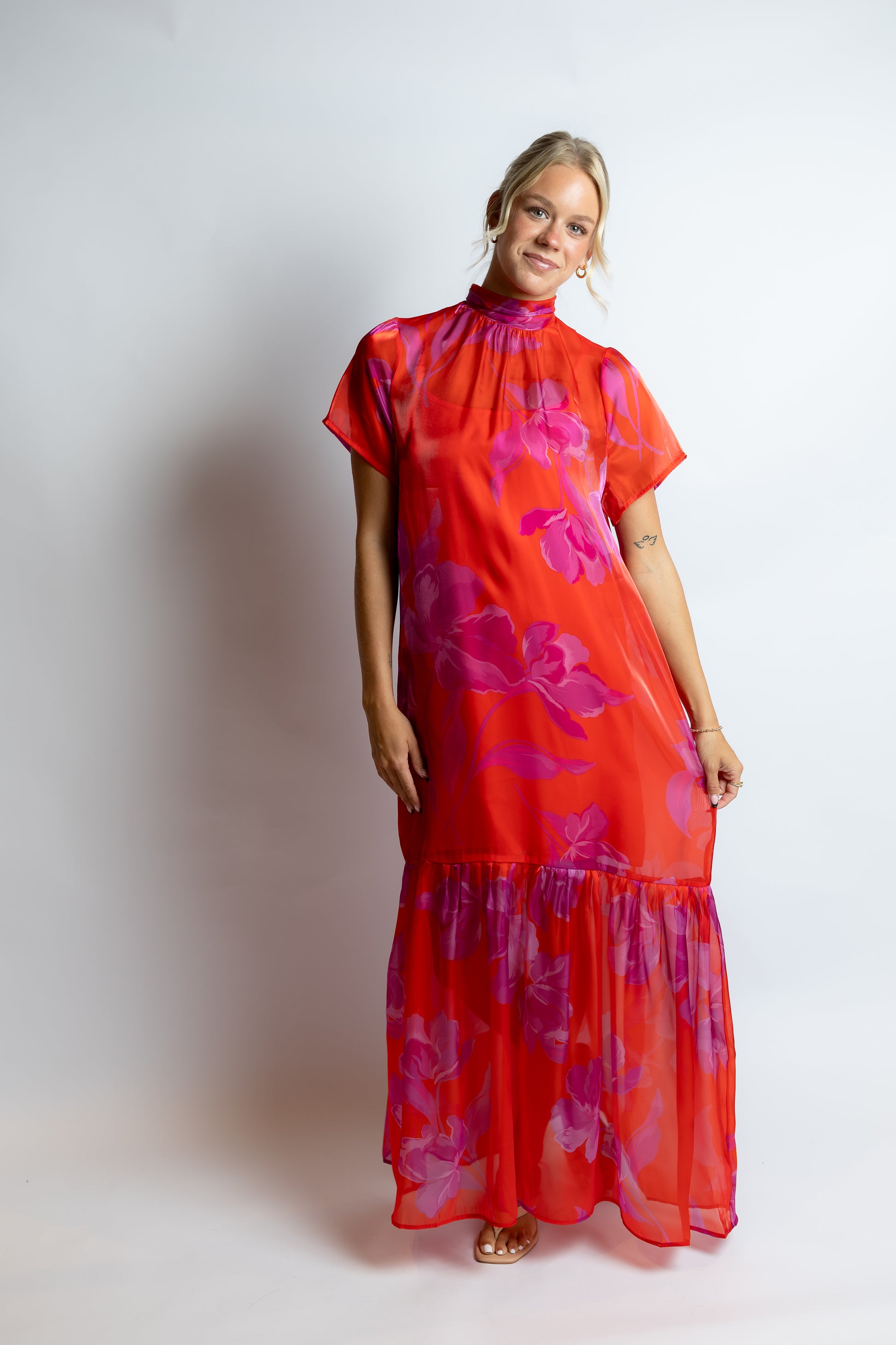 Woman wearing a red floral dress against a white background