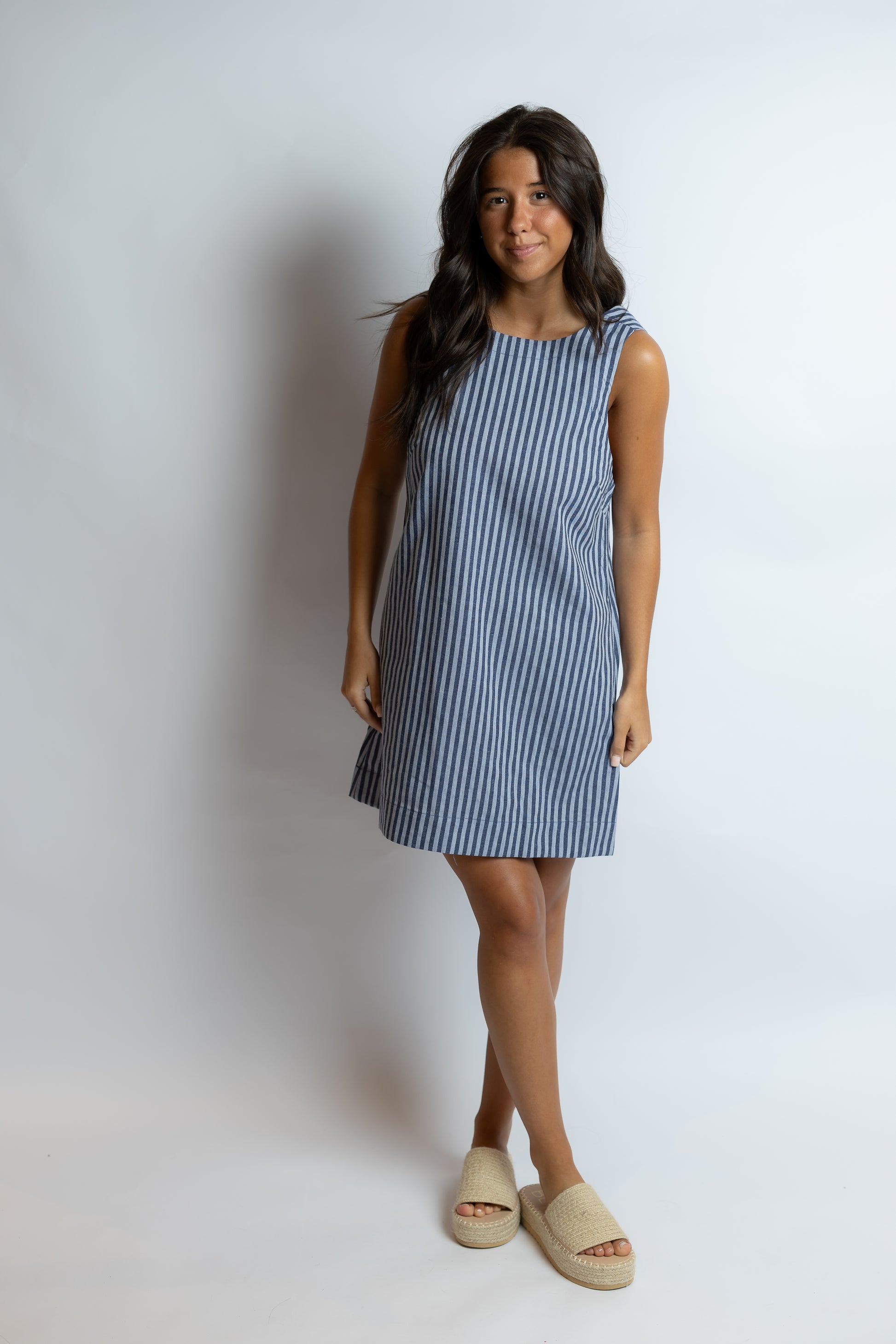 Woman wearing a blue and white striped dress against a plain background