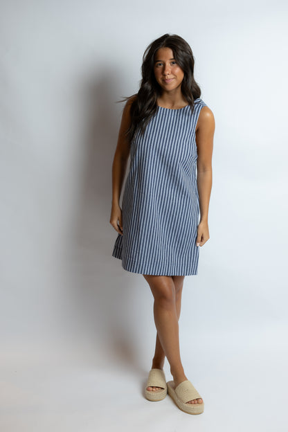 Woman wearing a blue and white striped dress against a plain background