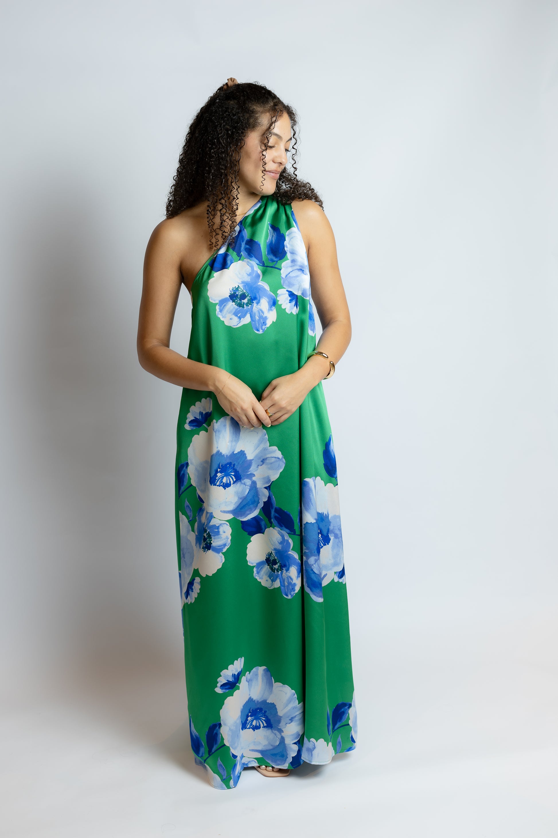 Woman wearing a green dress with blue floral patterns on a white background