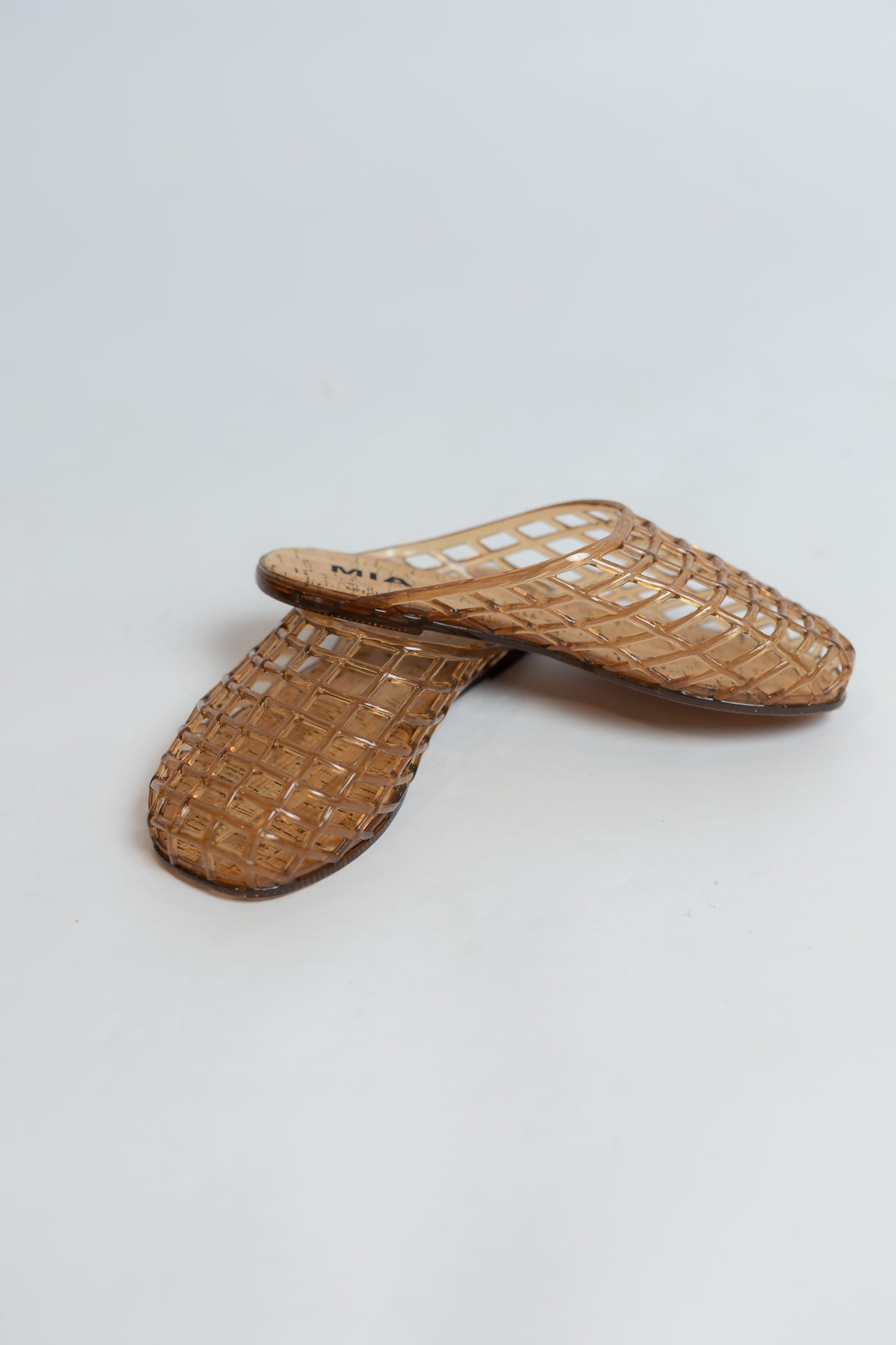 Pair of brown jelly flat sandals on a light gray background