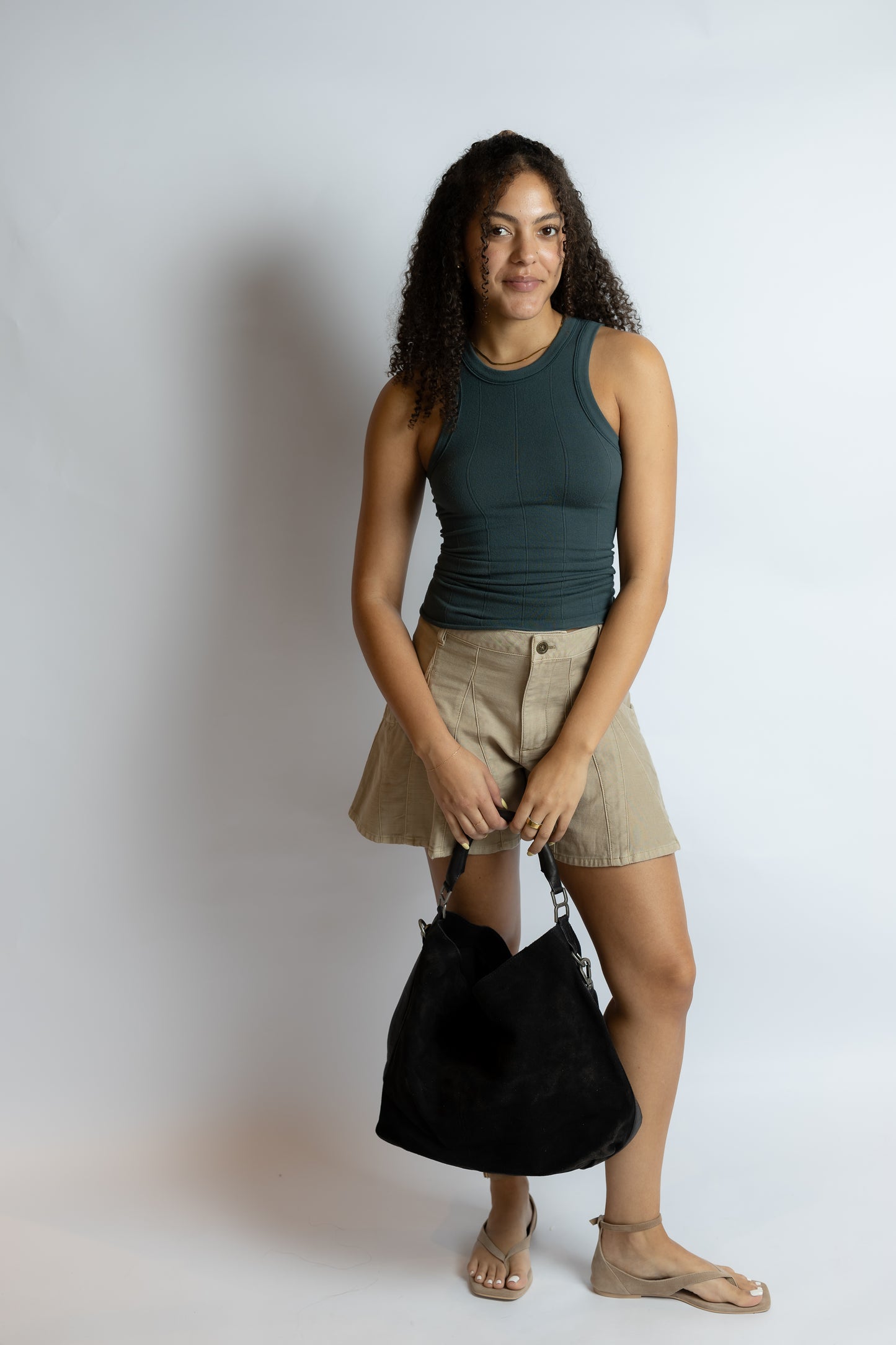 Woman holding a black bag against a plain background