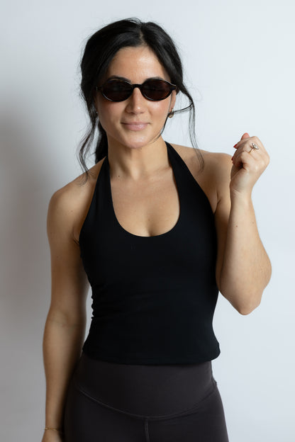 Woman wearing a black tank top and sunglasses on a white background