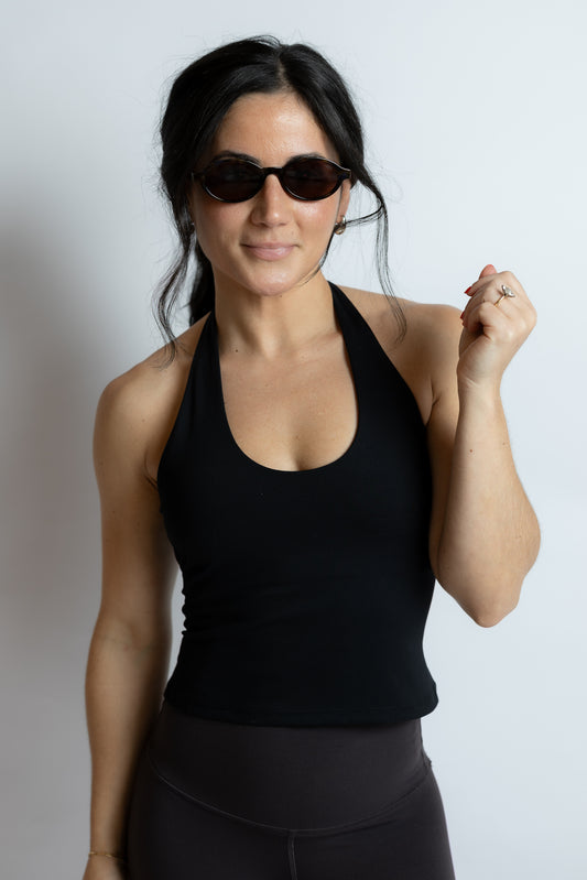 Woman wearing a black tank top and sunglasses on a white background
