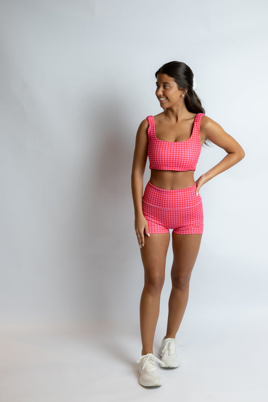 Woman wearing a pink checkered outfit on a white background