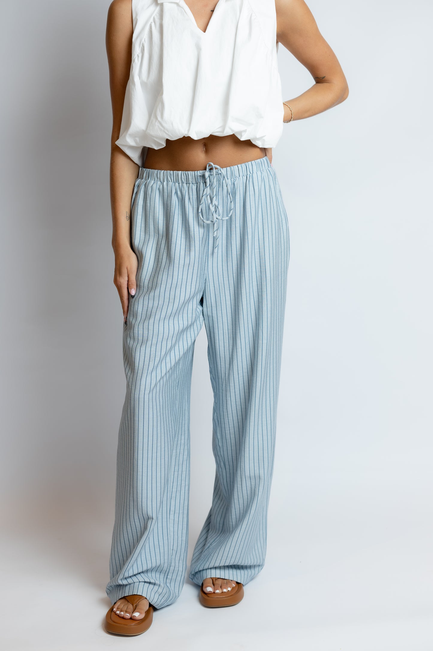 Person wearing a white top and blue striped pants on a plain background