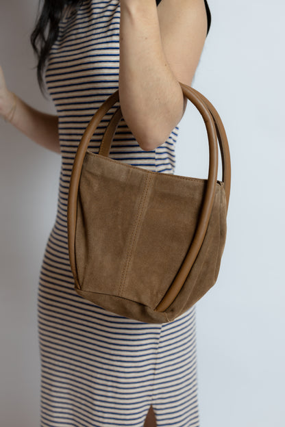 Person wearing a brown suede handbag with a blurred background