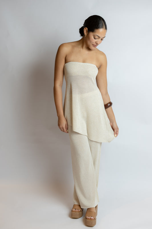 Woman wearing a beige strapless top and pants against a plain background