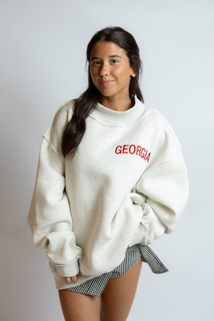 Woman wearing a white sweatshirt with 'GEORGIA' printed in red on a plain background