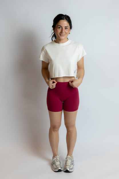 Woman wearing a white t-shirt and red shorts on a plain background