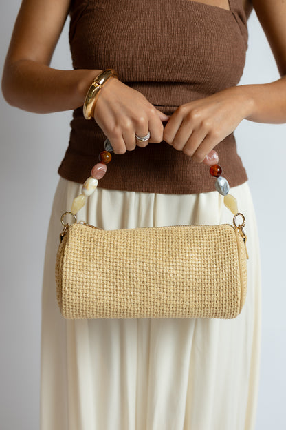 Person holding a woven handbag with a plain background
