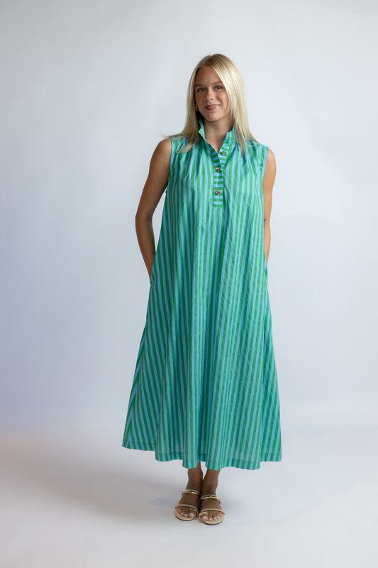 A woman modeling a sleeveless, button-front midi dress with vertical green and white stripes, standing against a light gray studio background.