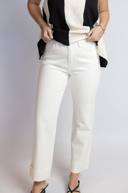 Person wearing a black and white striped top with white pants on a light gray background