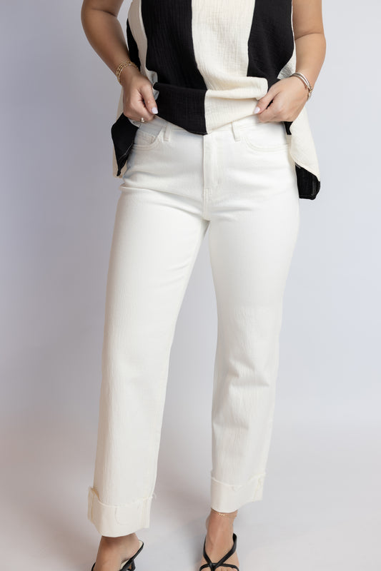 Person wearing a black and white striped top with white pants on a light gray background