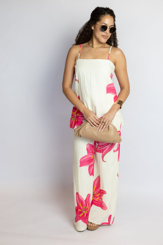 Woman wearing a white set with pink floral patterns on a plain background
