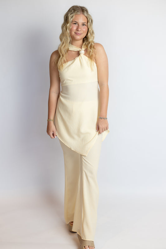 Woman wearing a light yellow sleeveless top and pants set on a white background