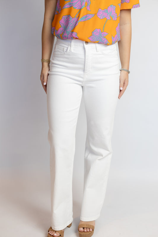 Person wearing white pants and a colorful top on a plain background