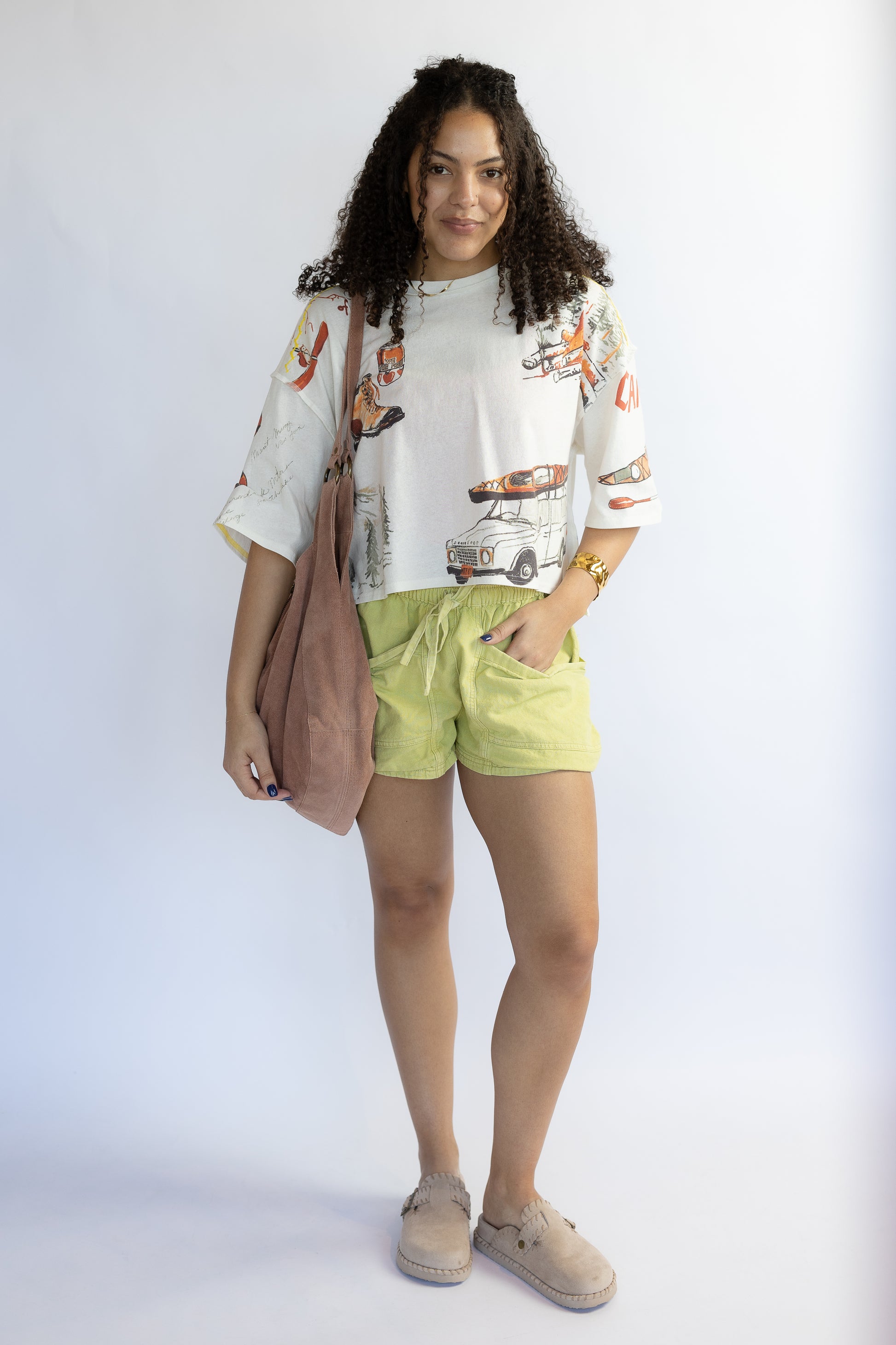 Woman wearing a graphic t-shirt and light green shorts with a white background