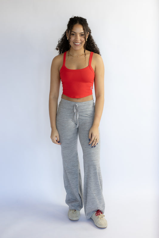 Woman wearing a red tank top and gray sweatpants on a white background