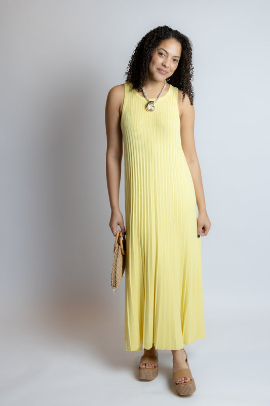 Woman wearing a yellow sleeveless dress on a plain background