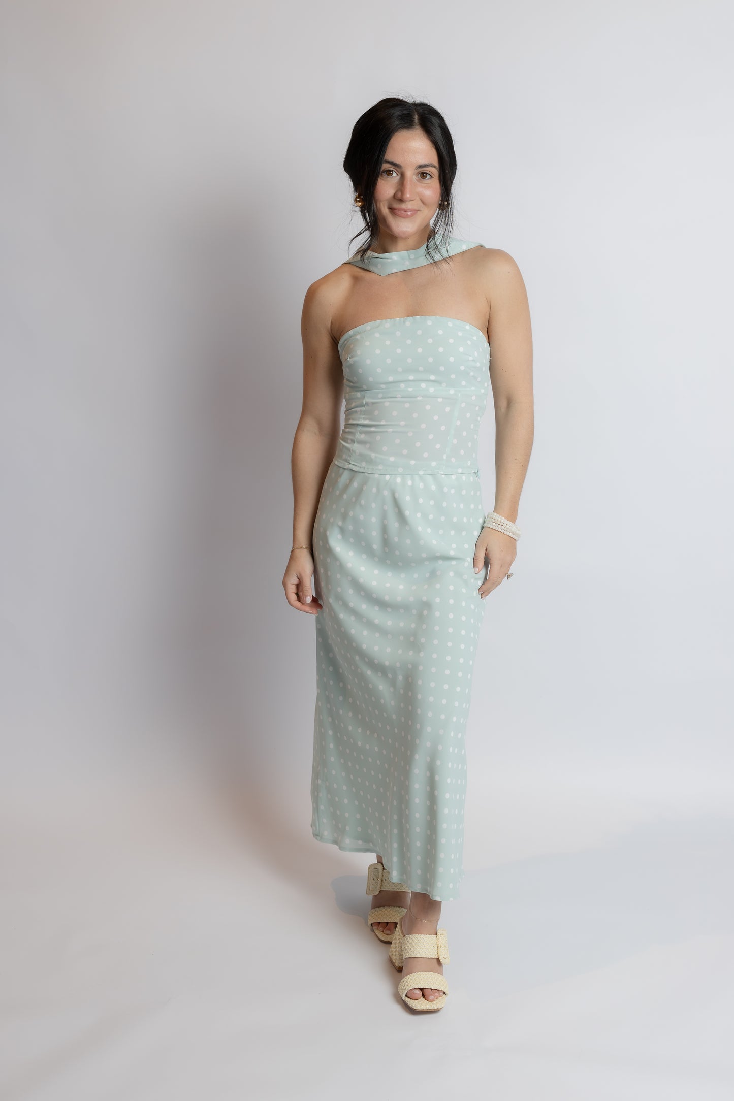 Woman wearing a light blue strapless dress against a plain background