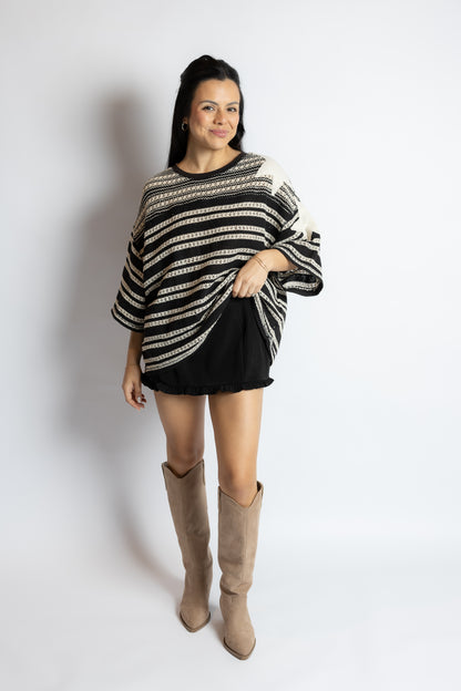 Woman wearing a black and white striped sweater with a plain background