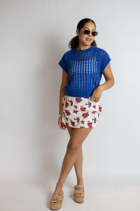 Woman wearing a blue top and patterned skirt on a plain background