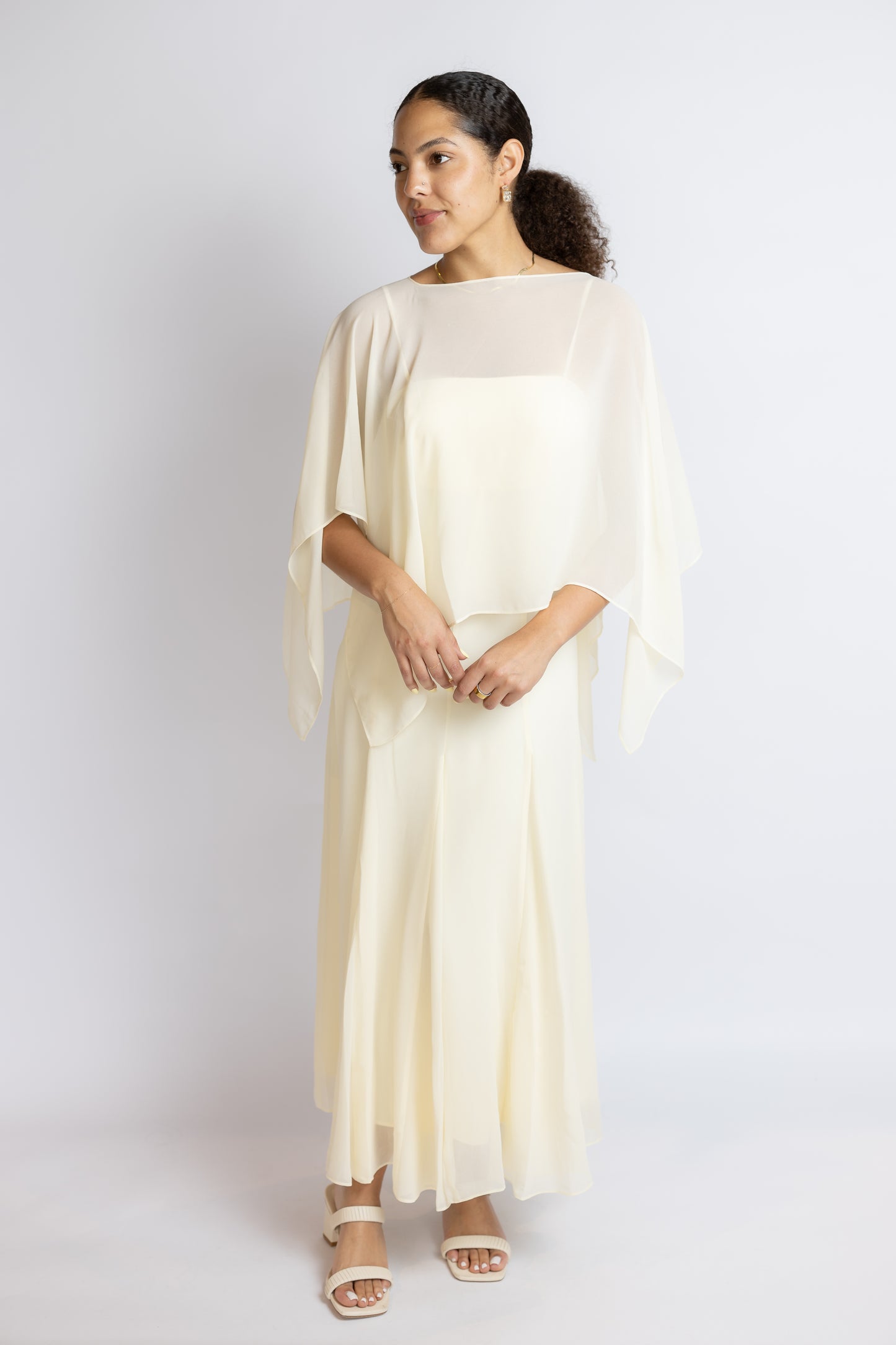 Woman wearing a flowing white dress against a plain background