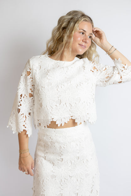 Woman wearing a white lace outfit against a plain background