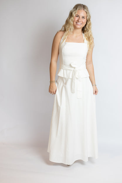 Woman wearing a white belted set against a plain background