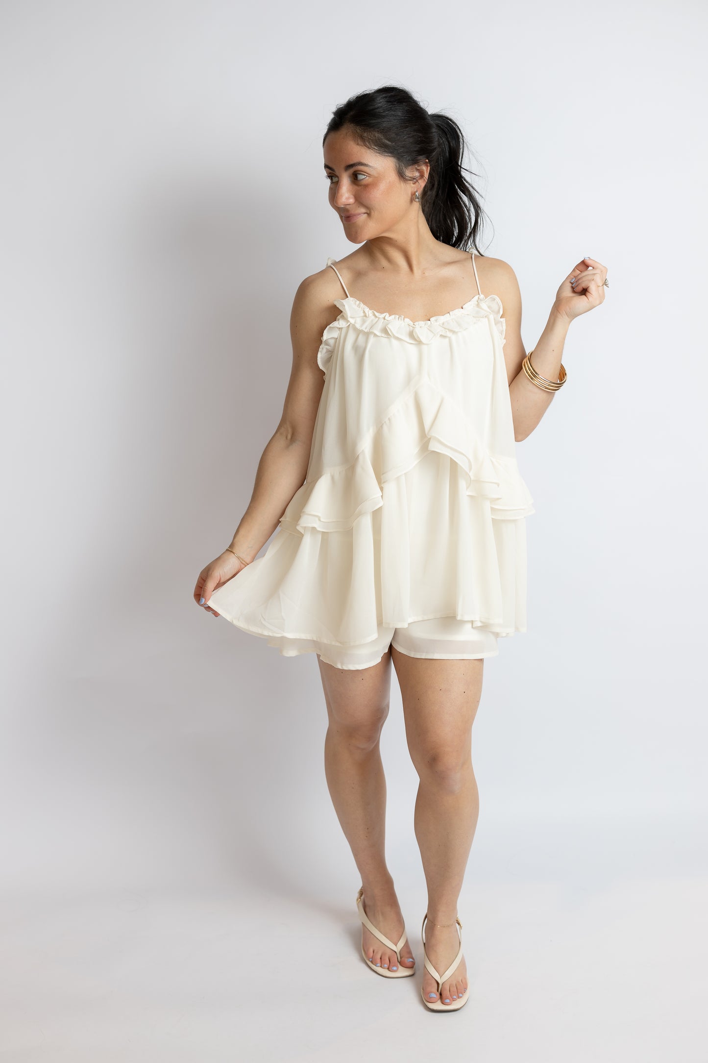 Woman wearing a white tie romper against a plain background