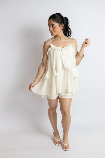 Woman wearing a white tie romper against a plain background