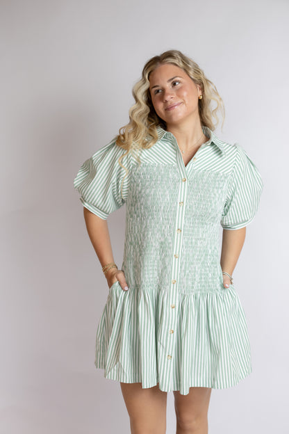 Woman wearing a green and white striped dress against a plain background